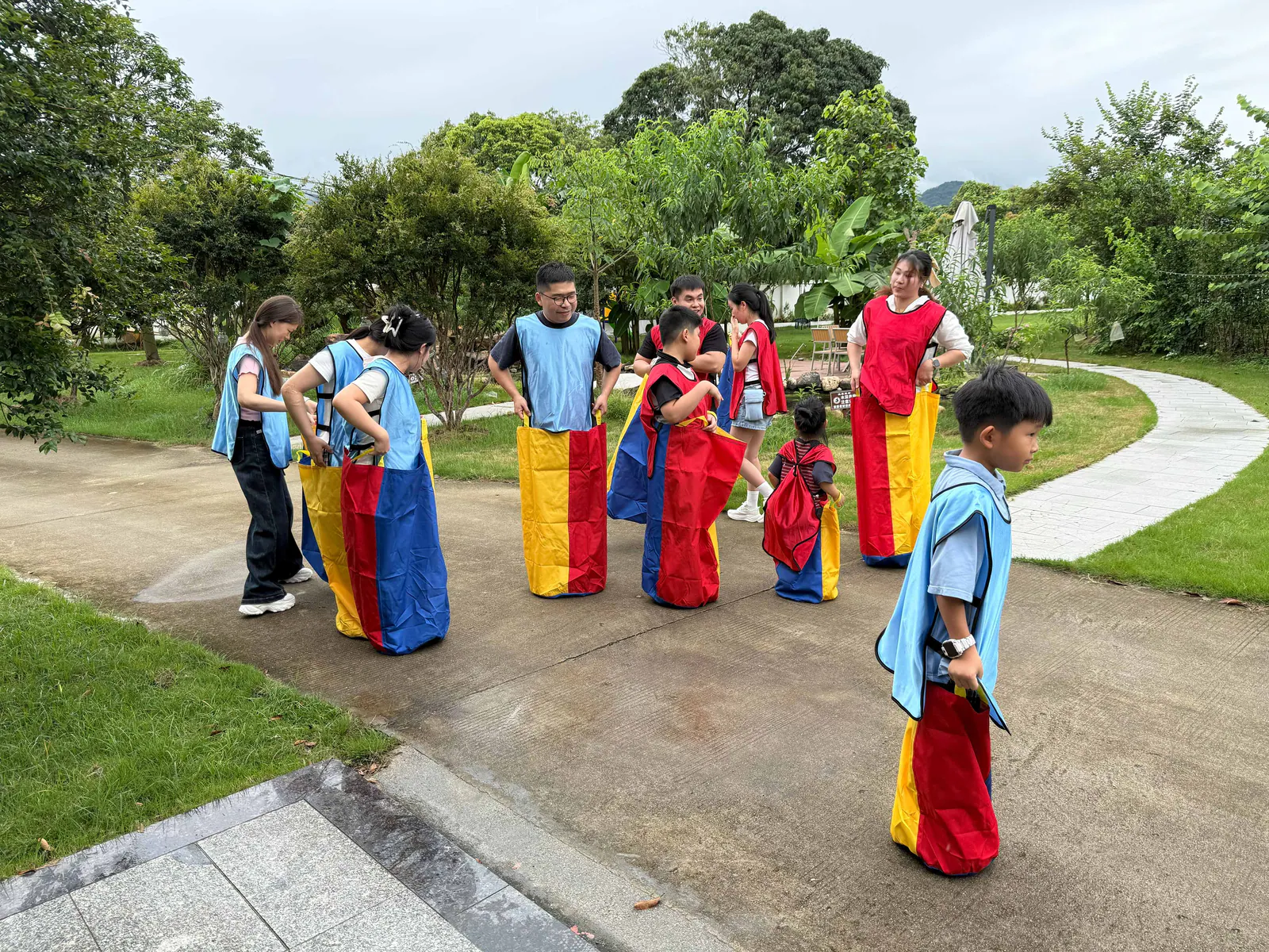 Red and blue teams preparing for the next round of the sack race on the grass